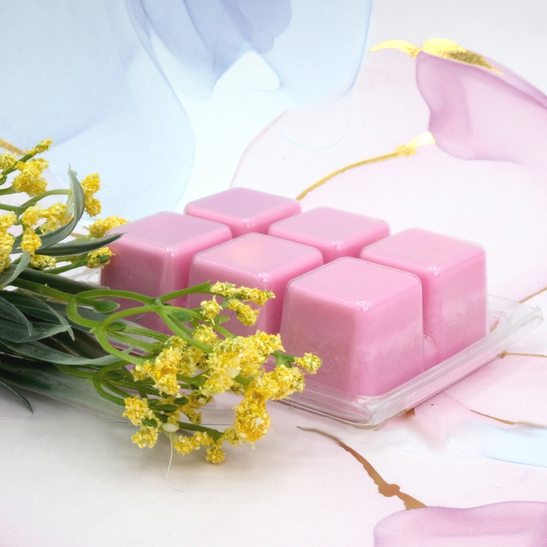 photo of pink colored wax melts on marble background with yellow flowers